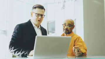 two business professionals looking at a laptop